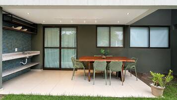 Uma sala de jantar com mesa e cadeiras de madeira, um vaso de planta e uma janela com vista.