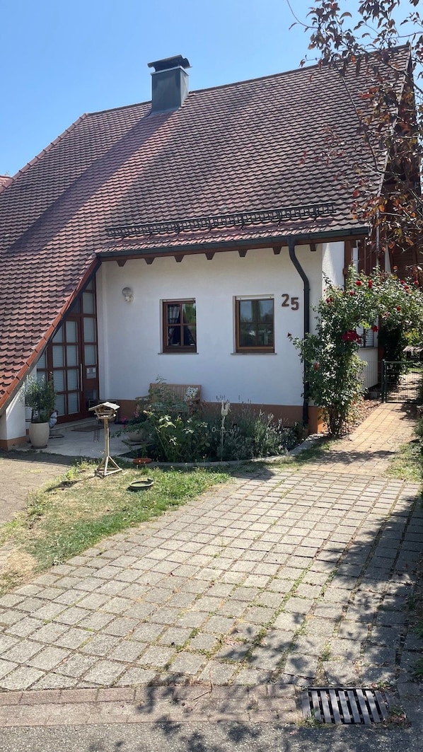 Una casa tradicional amb teulada inclinada, el número '25' a la paret i una calçada empedrada que condueix a l'entrada.