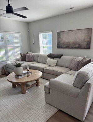 A modern living room with a sectional sofa, a coffee table, and a ceiling fan. - Delightful 2-bedroom house with AC in Sioux Falls (Sioux Falls)