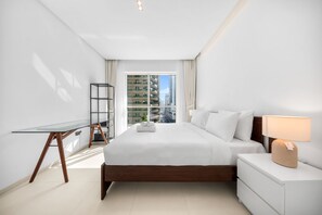 A modern hotel room with a large bed, a desk, a nightstand, and a window with a city view. - Stayshort - Chic 1 Bedroom Haven Perfect for 2 in Dubai Marina (Dubai)