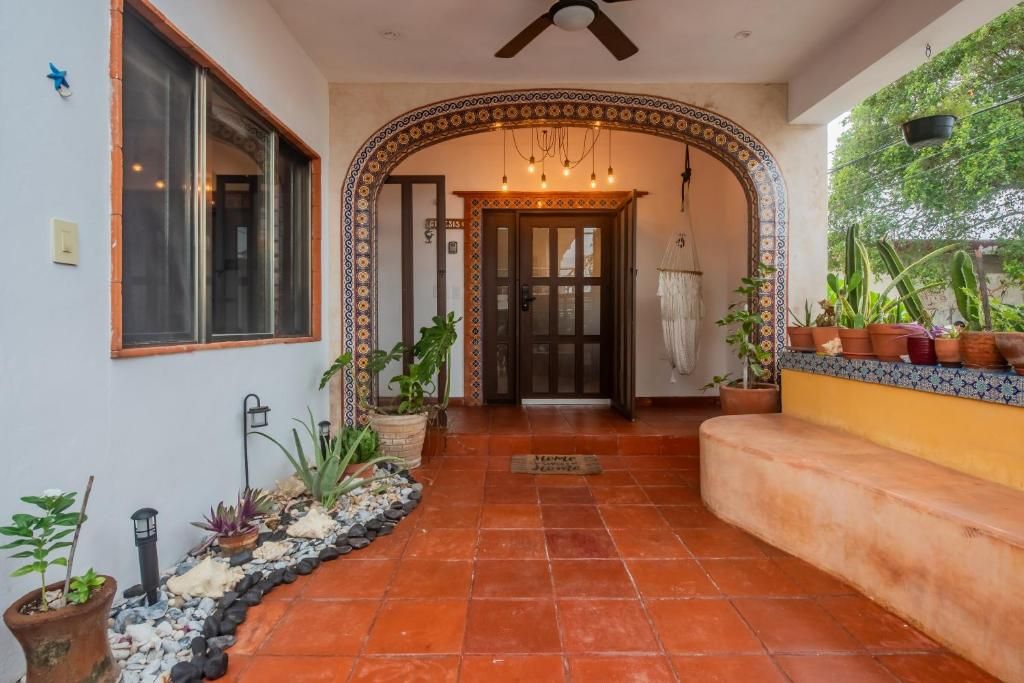A hallway with a tiled floor, a door with glass panels, and potted plants.