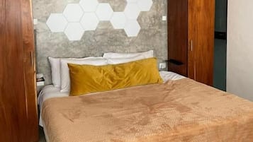 A bedroom with a bed, wooden headboard, and a hexagonal wall design.