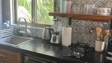 A kitchen with a built-in microwave, toaster, and coffee maker. There is a window providing natural light and a view of greenery outside.