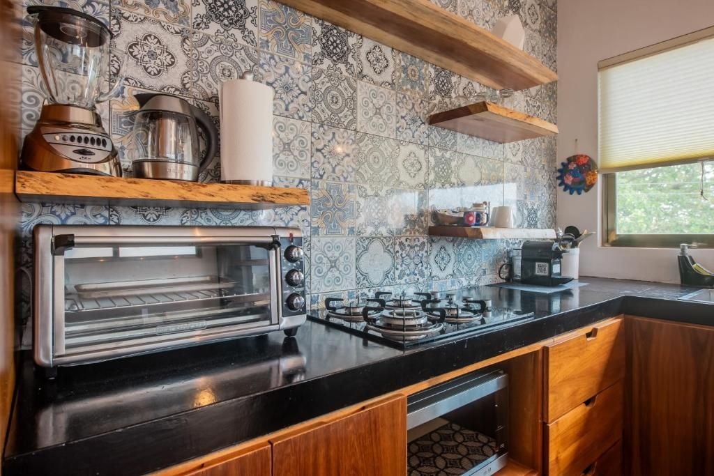 Una cocina con horno empotrado, estufa a gas y licuadora.