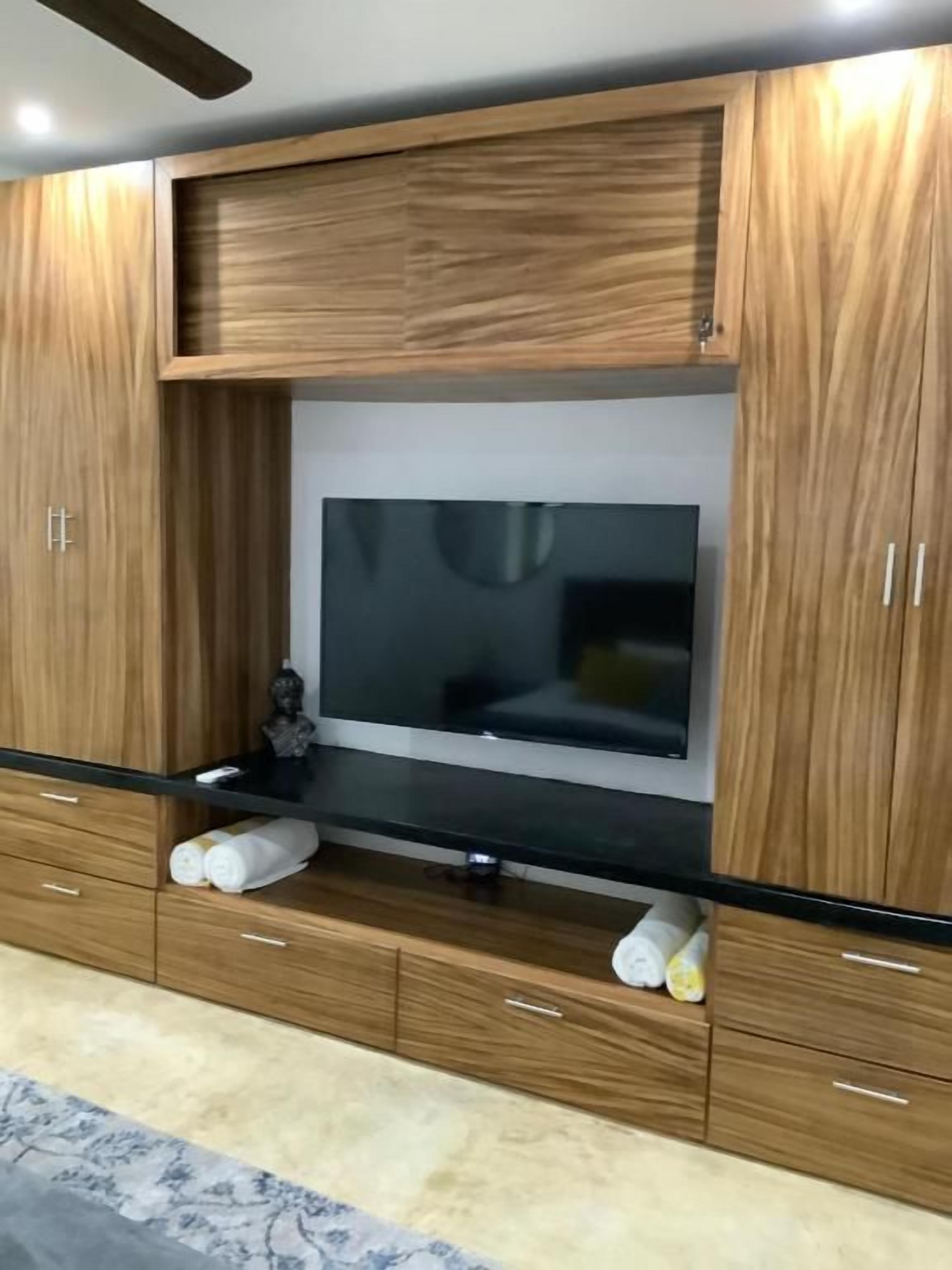 Un salon moderne avec un téléviseur à écran plat fixé à un meuble en bois, un plan de travail noir et des tiroirs de rangement intégrés.