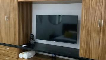 Un salon moderne avec un téléviseur à écran plat fixé à un meuble en bois, un plan de travail noir et des tiroirs de rangement intégrés.