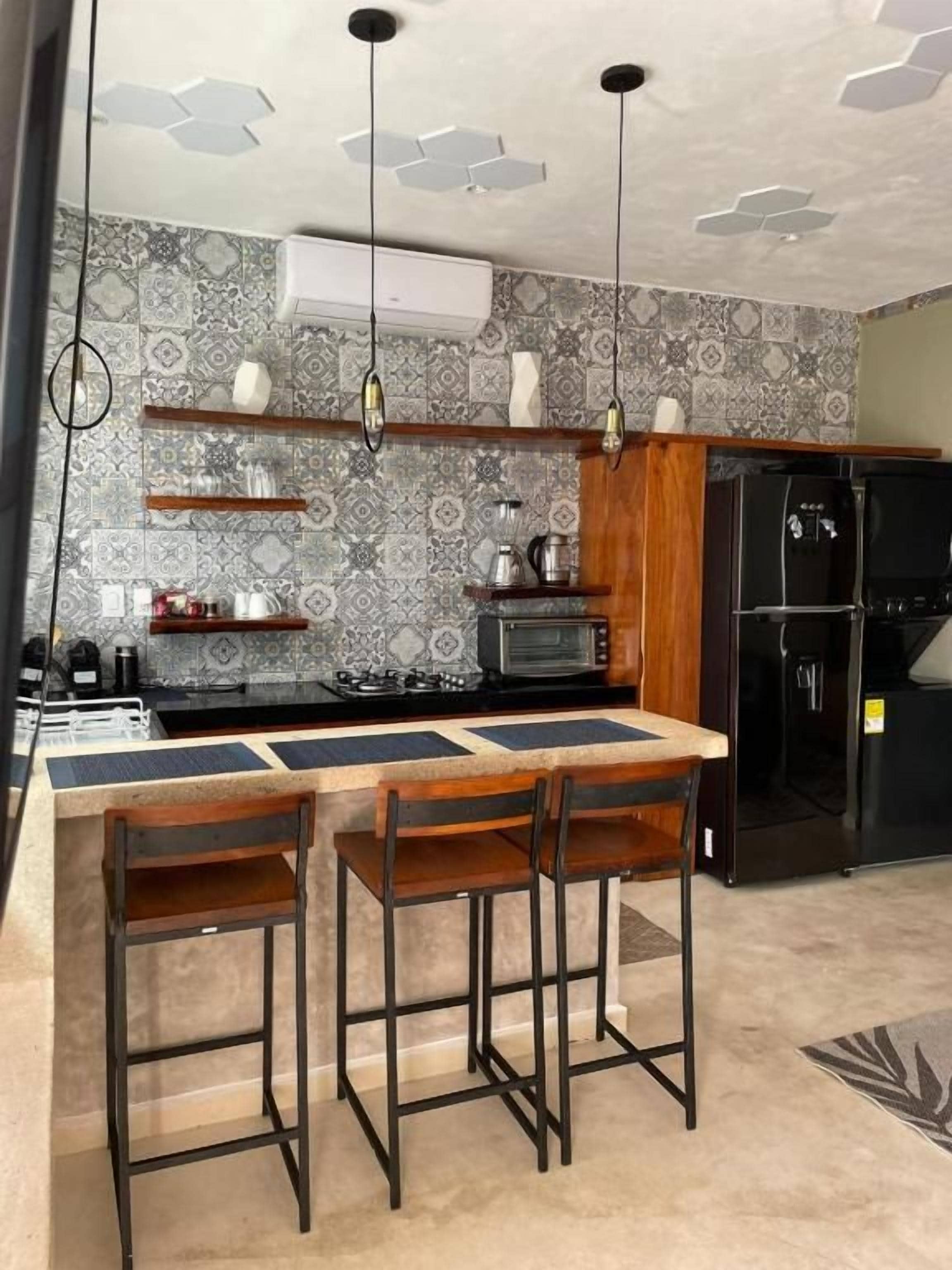 A kitchen with a bar area, a refrigerator, and a microwave.