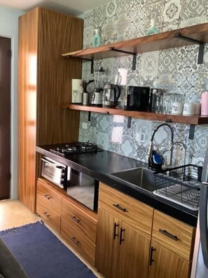Una cocina con armarios de madera, encimera negra y un salpicadero con diseño.