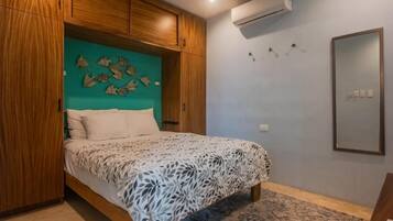 Un dormitorio con cama, armario de madera, aire acondicionado instalado en la pared y un espejo.
