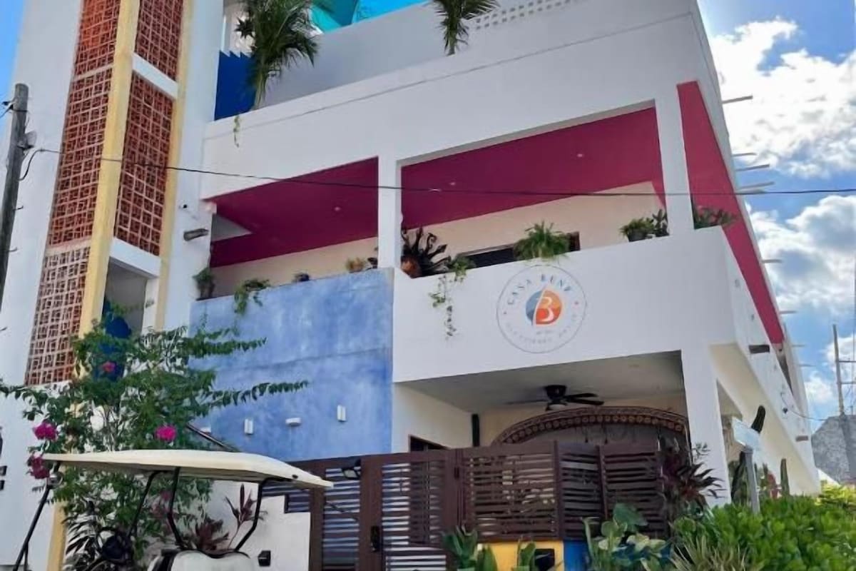 Un edificio a più piani con un ingresso chiuso da cancello, un golf cart parcheggiato davanti e cielo sereno.