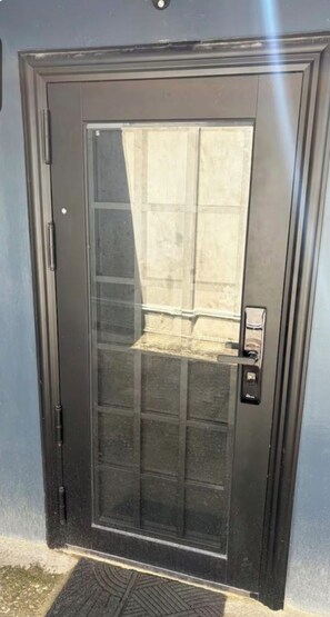 Uma porta com painel de vidro e puxador de metal.