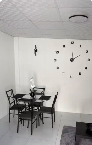 Un coin repas comprenant une horloge murale, une table et des chaises.