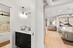 Une salle de bain moderne avec un grand miroir, des meubles noirs et un plan de travail blanc.
