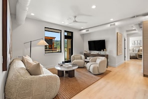 Un salon moderne avec un canapé, des fauteuils, une table basse et un téléviseur.