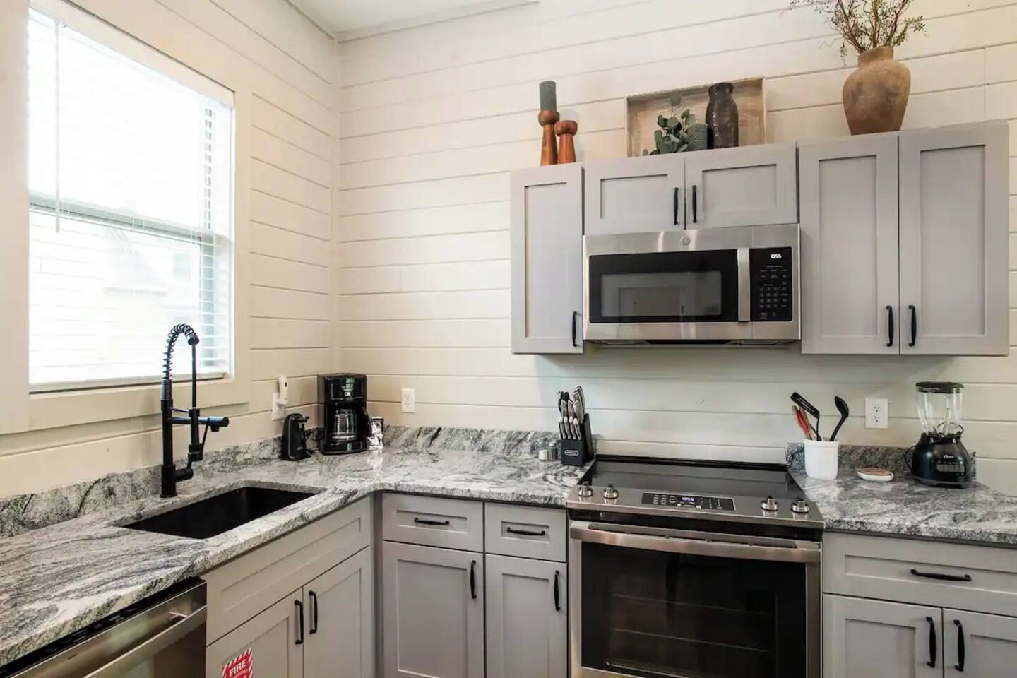 A kitchen with a granite countertop, stainless steel appliances, and white cabinetry.