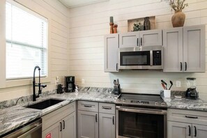 A kitchen with a granite countertop, stainless steel appliances, and white cabinetry. - Lake Access-Resort Beach-Modern-Games-Hot Tub (Sevierville)