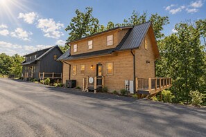 A two-story wooden house with a front porch, a garage, and a driveway. - Lake Access-Resort Beach-Modern-Games-Hot Tub (Sevierville)