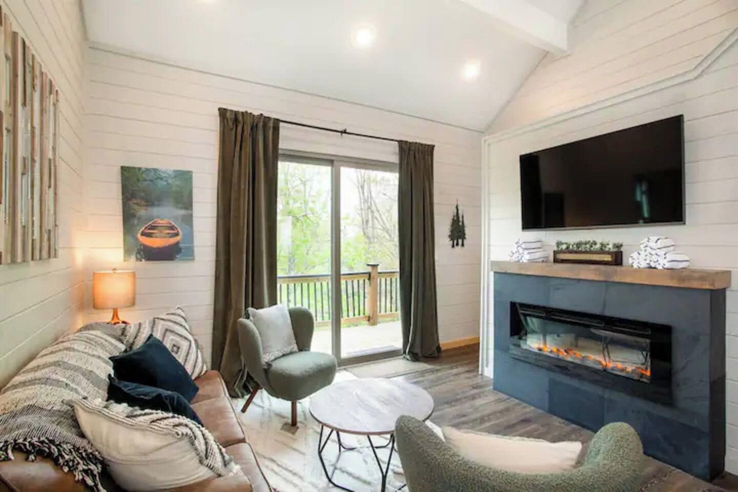 A cozy living room with a fireplace, a sofa, a chair, and a television.
