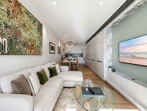 Ein modernes Wohnzimmer mit einer Couch, einem Glastisch und einem großen Gemälde an der Wand.