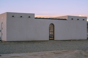 A building with a flat facade, a central arched entrance, and a small bench inside.