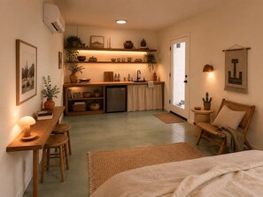 Un ambiente compatto con angolo cottura, zona pranzo e salotto con una sedia e un tavolo.
