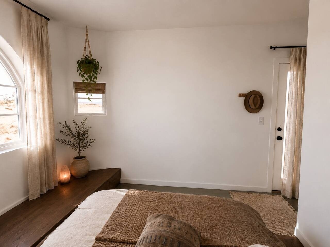 Une chambre à coucher avec un lit, une fenêtre, une porte et une plante suspendue.