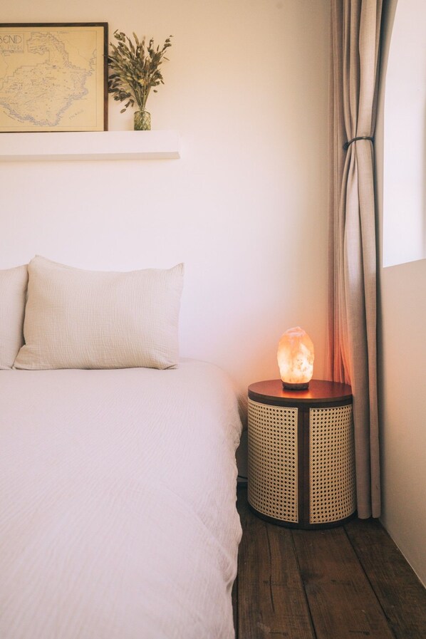 A bedroom with a bed, a small round table with a salt lamp, a map on the wall, and a curtain.