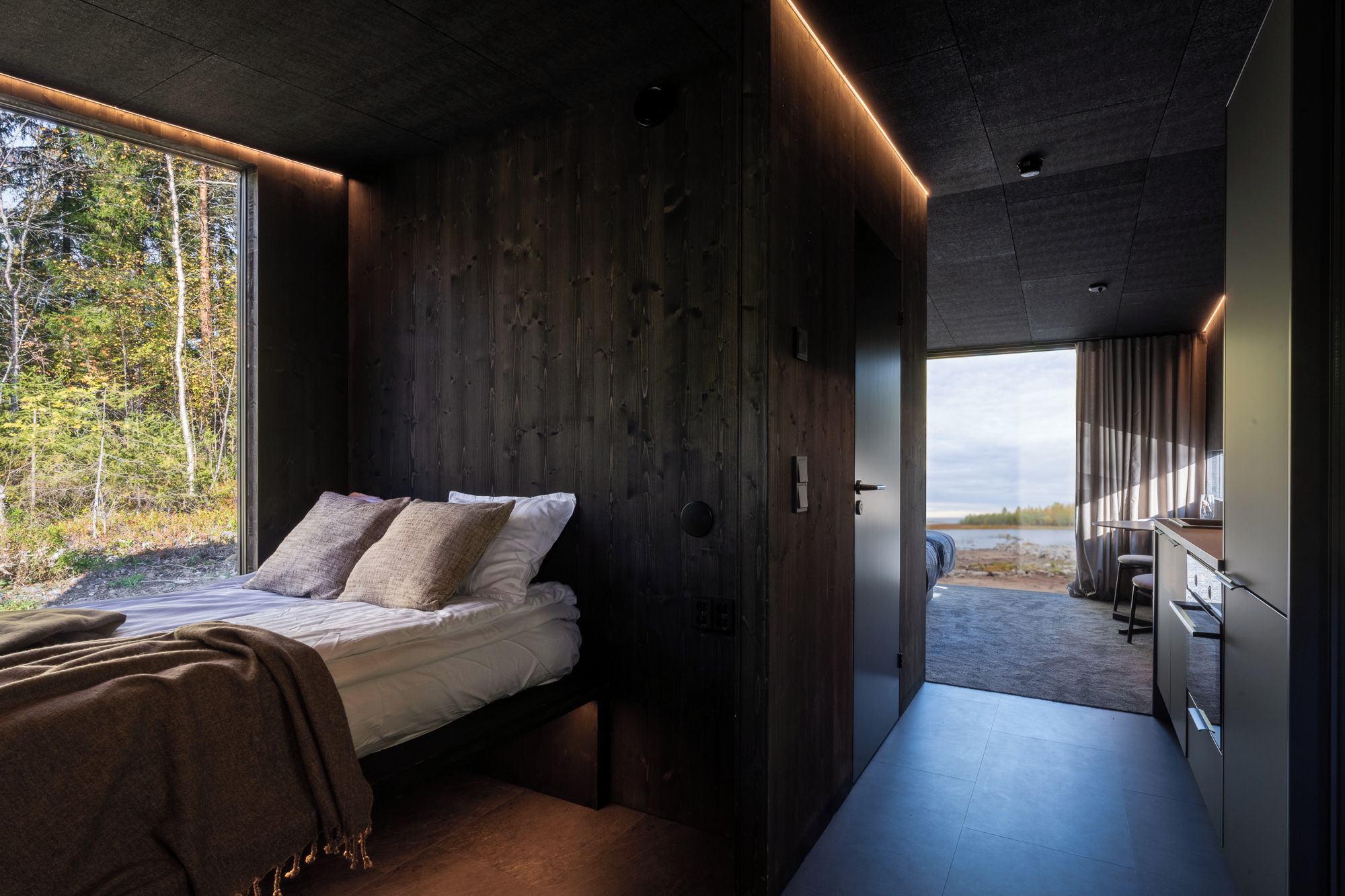 A modern interior with a bed, wooden walls, and a view of the outdoors.