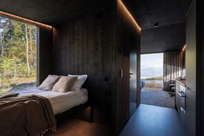 A modern interior with a bed, wooden walls, and a view of the outdoors.