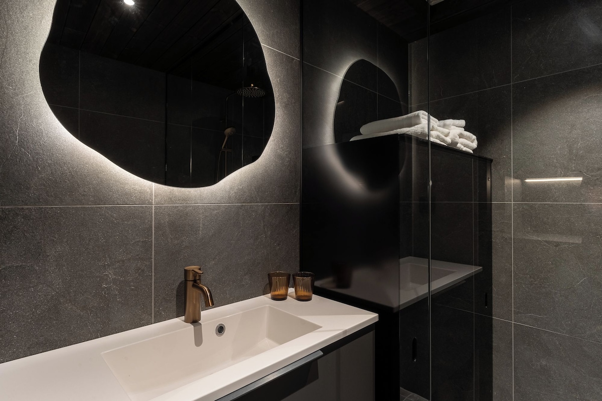 A modern bathroom with a large sink, a mirror, and a glass-enclosed shower.