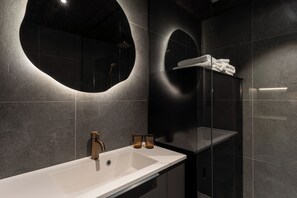 A modern bathroom with a large sink, a mirror, and a glass-enclosed shower. - Aurora sea resort  (Kuivaniemi)