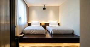 A hotel room with two beds, a bedside table, a nightstand, and a ceiling-mounted projector. - TangFangCiyunYaju (Datong)