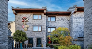 Un edificio tradicional con fachada moderna, que destaca por una entrada con puerta de madera y un cartel con caracteres chinos.