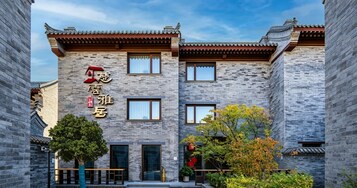 Un edificio tradicional con fachada moderna, que destaca por una entrada con puerta de madera y un cartel con caracteres chinos.