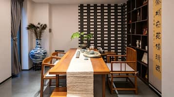 A dining area with a wooden table, chairs, a vase, and a decorative wall panel.