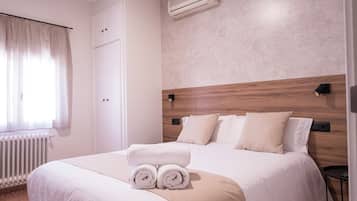 Habitación de hotel con una cama grande, un radiador, un armario y un aire acondicionado de pared.