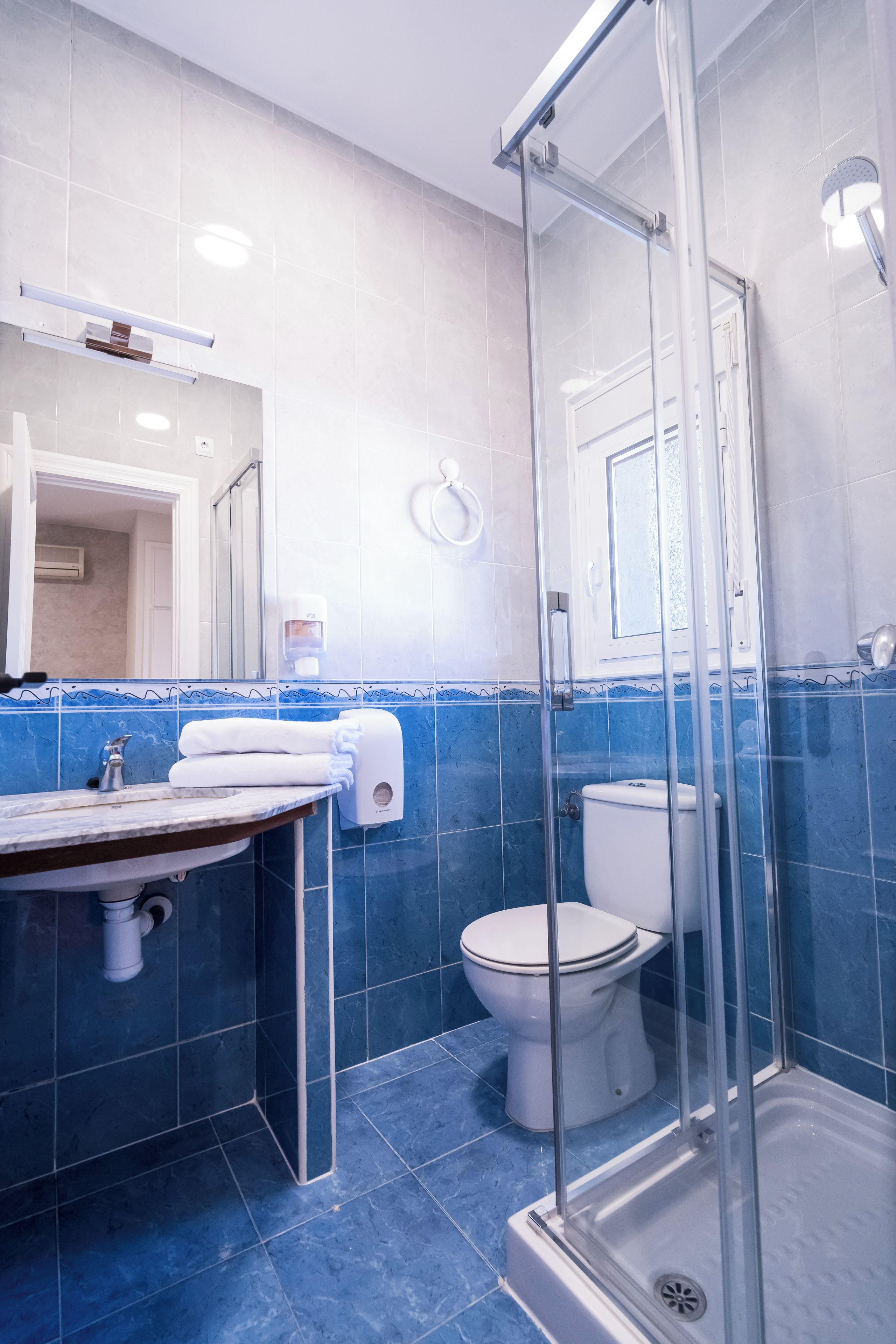 Un baño moderno con ducha envuelta en vidrio, un inodoro y un lavabo con encimera de mármol.