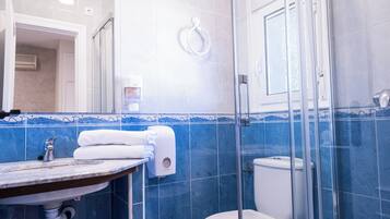 Un baño moderno con ducha envuelta en vidrio, un inodoro y un lavabo con encimera de mármol.