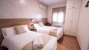 Habitación de hotel con dos camas, una mesita, un radiador y un armario.