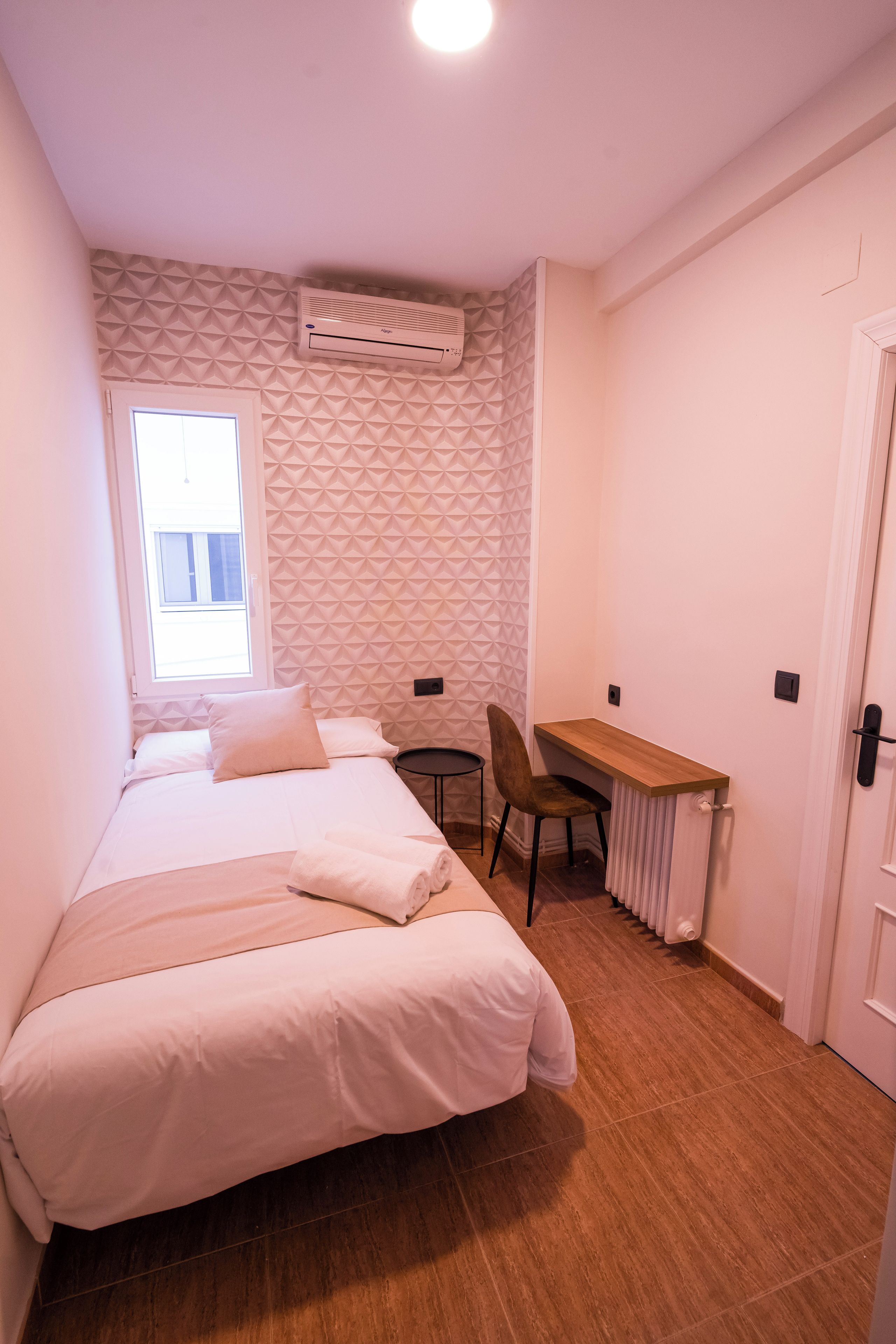 Un dormitorio con una cama, un escritorio y una silla.