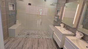 Ein modernes Badezimmer mit einer Duschkabine aus Glas, einem Waschtisch mit Spiegel und einem gemusterten Teppich.