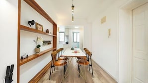 Ein Essbereich mit einem weißen Tisch, sechs Stühlen und einem Holzbodenregal mit Dekoration.