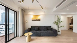 Ein modernes Wohnzimmer mit einer Couch, einem Couchtisch und einem großen Fenster mit Blick auf Gebäude.