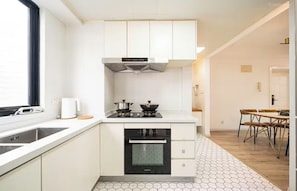 A compact kitchen with white cabinets, a built-in oven, and a window.