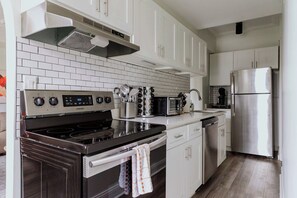 A modern kitchen with white cabinetry, a stainless steel refrigerator, a built-in oven, and a range with a digital control panel. - Luxury Designer Apartment 1003|Gold Coast/Old Town (Chicago)