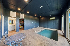 Ein Poolbereich mit Metalltisch und -stühlen, ein kleiner Innenpool und eine Tür zu einem Badezimmer.