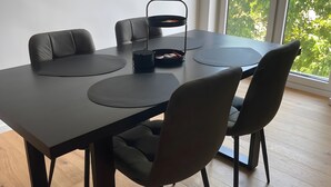 Ein moderner Essbereich mit einem schwarzen Tisch, passenden Stühlen und einem schwarzen Beistelltisch mit einem Korb.