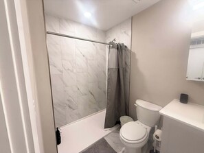 A modern bathroom with a shower, toilet, and a mirror above the sink. - Luxury Studio | 1 Bed | Northern Liberties (Philadelphia)
