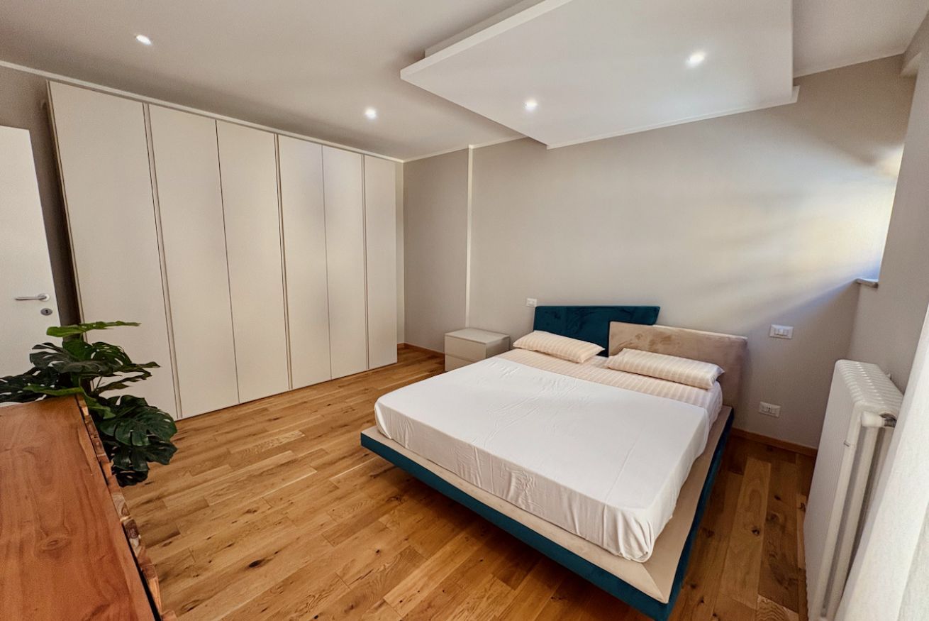 Una camera da letto con un letto, comodini, un armadio e un termosifone.
