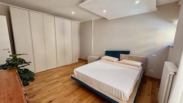 Una camera da letto con un letto, comodini, un armadio e un termosifone.
